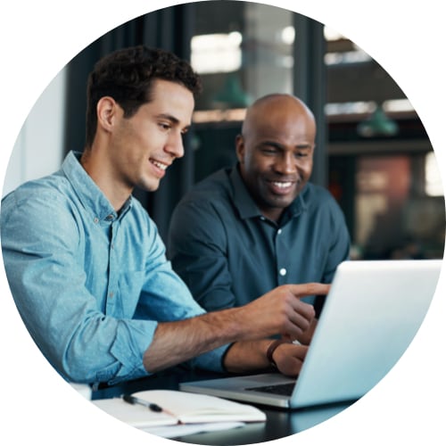 Two male professionals having a discussion in an office using a laptop.