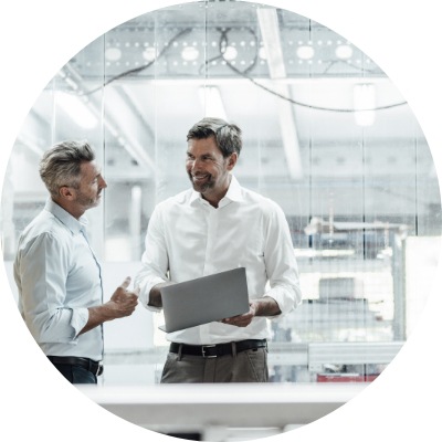 Smiling engineer discussing over laptop with male colleague in factory.