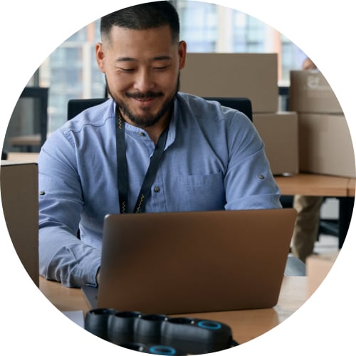 Young IT professional preparing for office moving with cardboard boxes in the background.