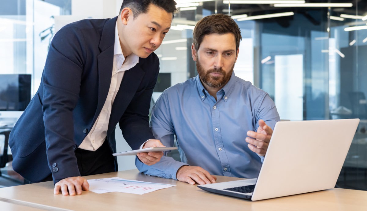 An IT specialist demonstrates a concept on a computer screen to a business client.