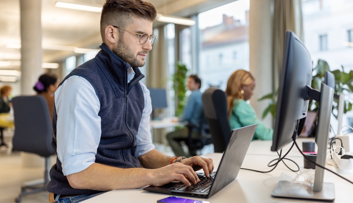 A young IT professional is working on a computer in an office.