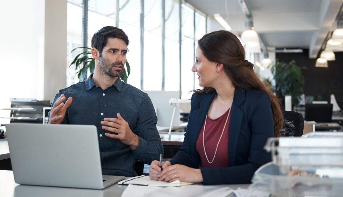 An IT professional gestures towards the computer screen, explaining a complex issue to a client.