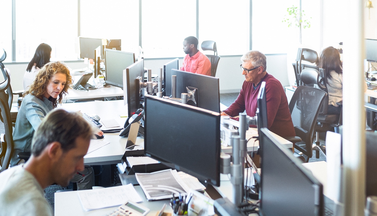 Employees working at computer desks in a bright, modern open-plan office environment.