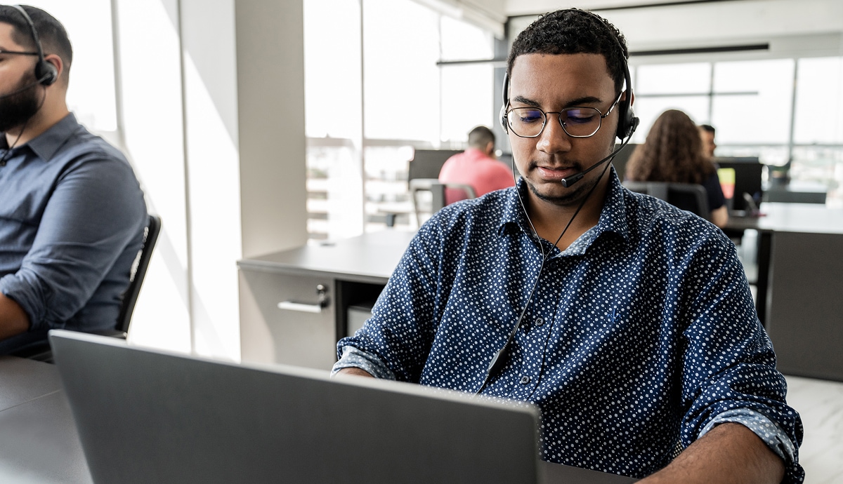 Office employees wearing headsets, working at their computers.