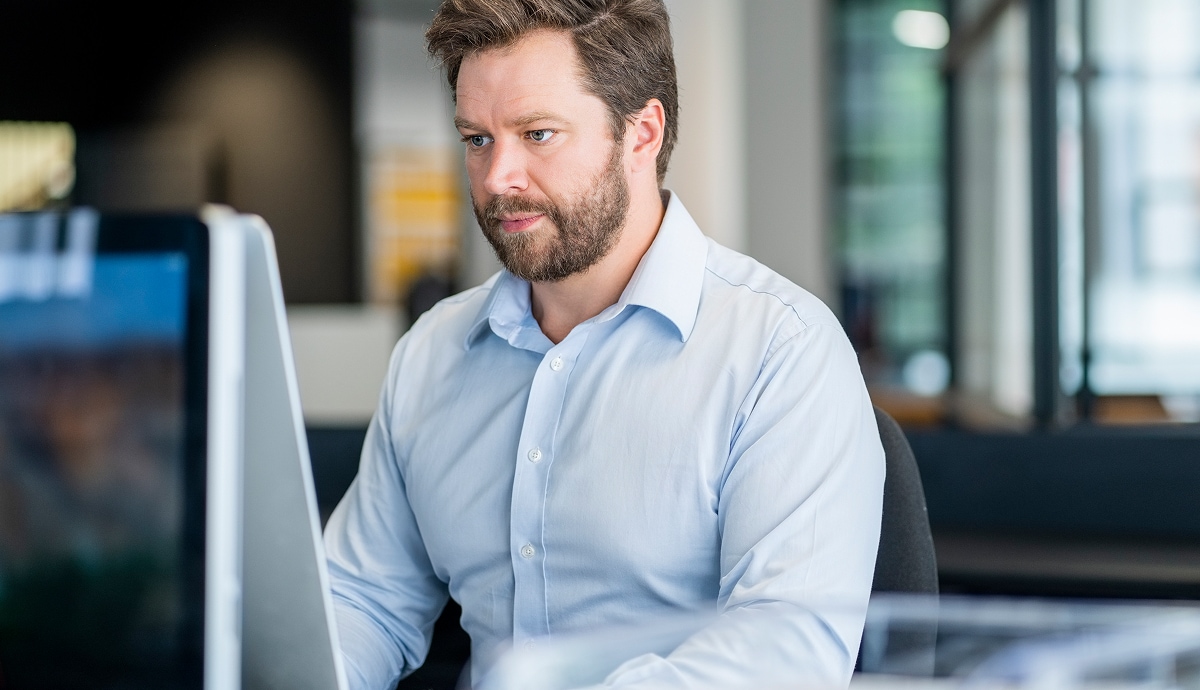 An IT specialist concentrating on his computer in a modern office workspace.