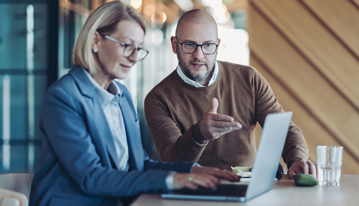 Two professionals reviewing information on a laptop during a focused office discussion.