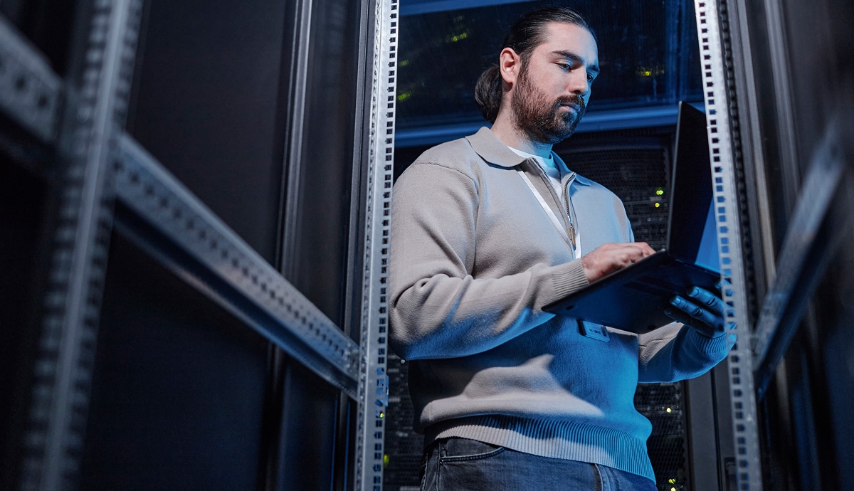IT professional managing servers while working on a laptop in a data center.