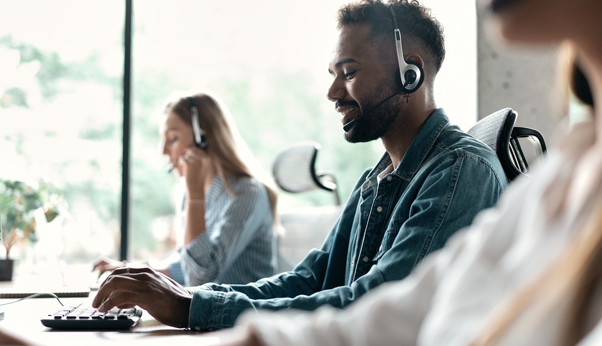 Customer service agents wear headsets assisting callers in office.