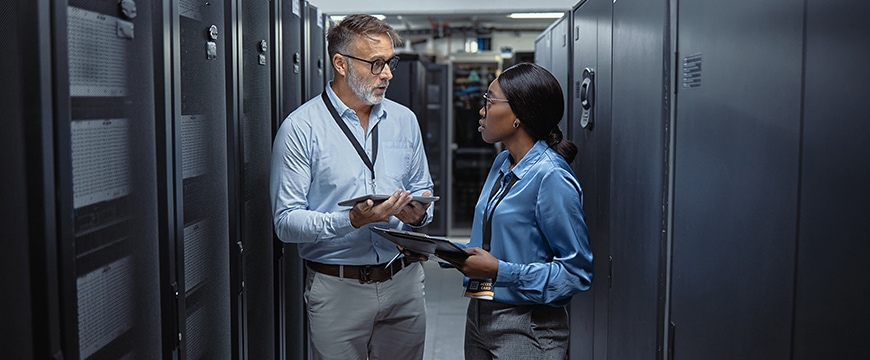 Two IT tech programmers collaborating in server room.