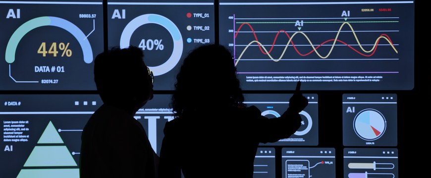 Two people viewing AI analytics dashboards and charts on large screens