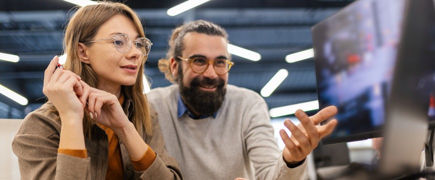 Two office professionals reviewing content together on a desktop monitor