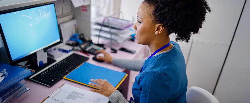 Black woman using computer to work as nurse in the private clinic.