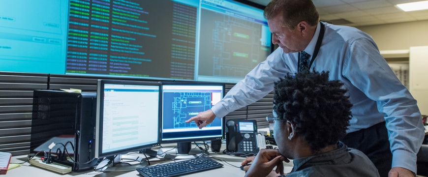 Colleagues examine cybersecurity information displayed in a security operations workspace