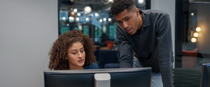 Two professionals reviewing project together while looking at computer screen in office