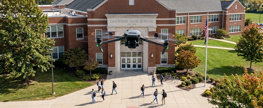 blog hero image of a drone camera flying in front of a high school campus
