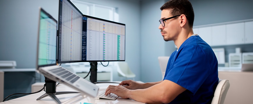 Hispanic Doctor Using Spreadsheet To Manage Medical Billing Data Efficiently