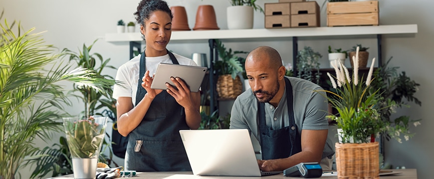 Small business owners in a flower shop using mobile devices.