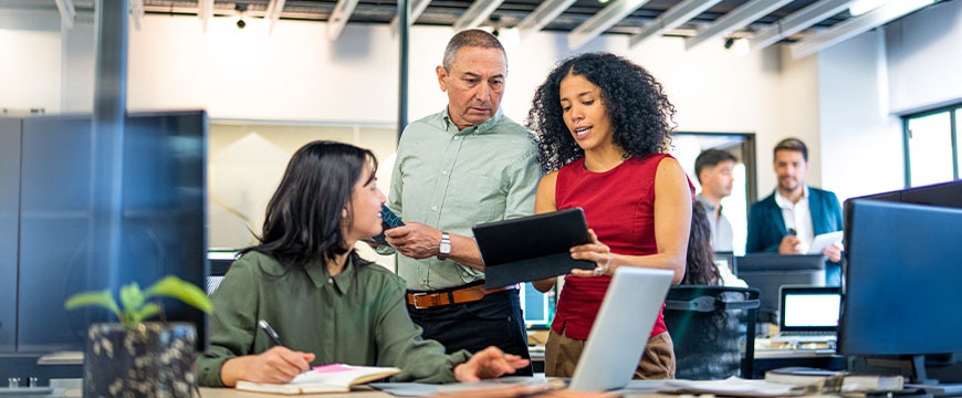 Diverse office employees navigating digital workflows on multiple devices