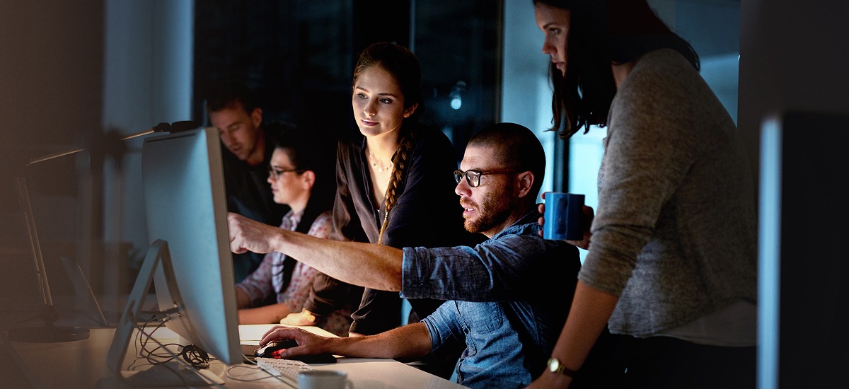 Team collaborating at computer during late-night work session.