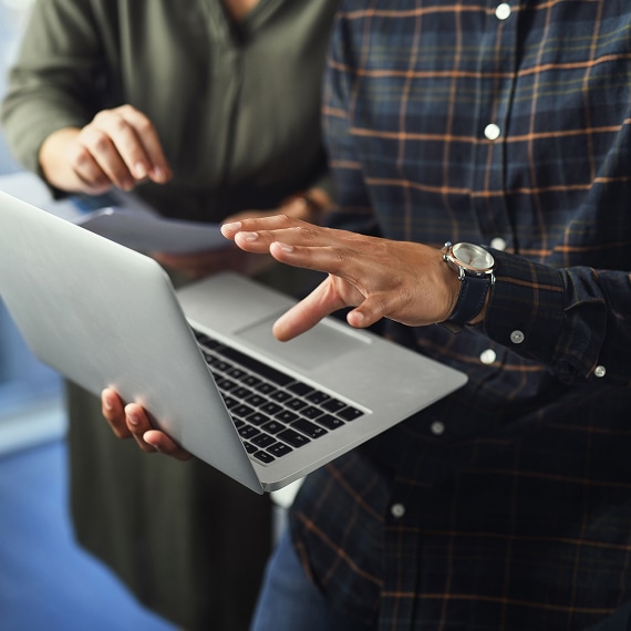 Close-up of hands navigating laptop during focused business discussion.