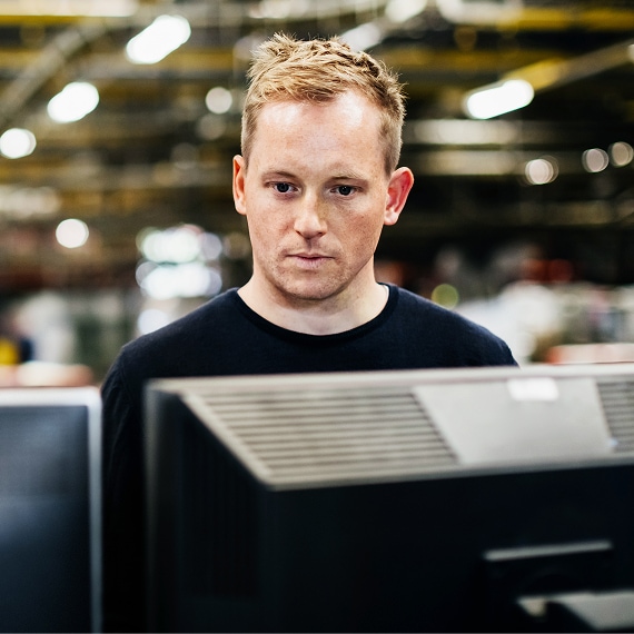 Technician concentrating on monitor inside manufacturing environment.
