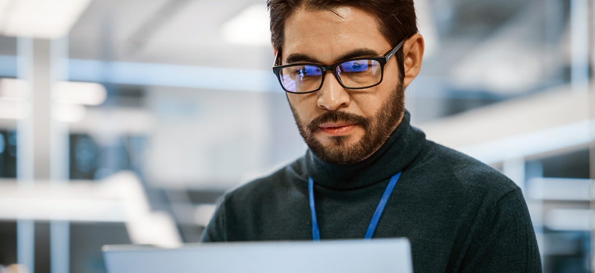 Software developer reviewing code on laptop in modern office workspace.