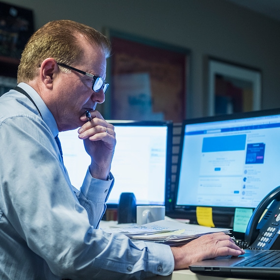Security analyst reviewing data on dual monitors in office.