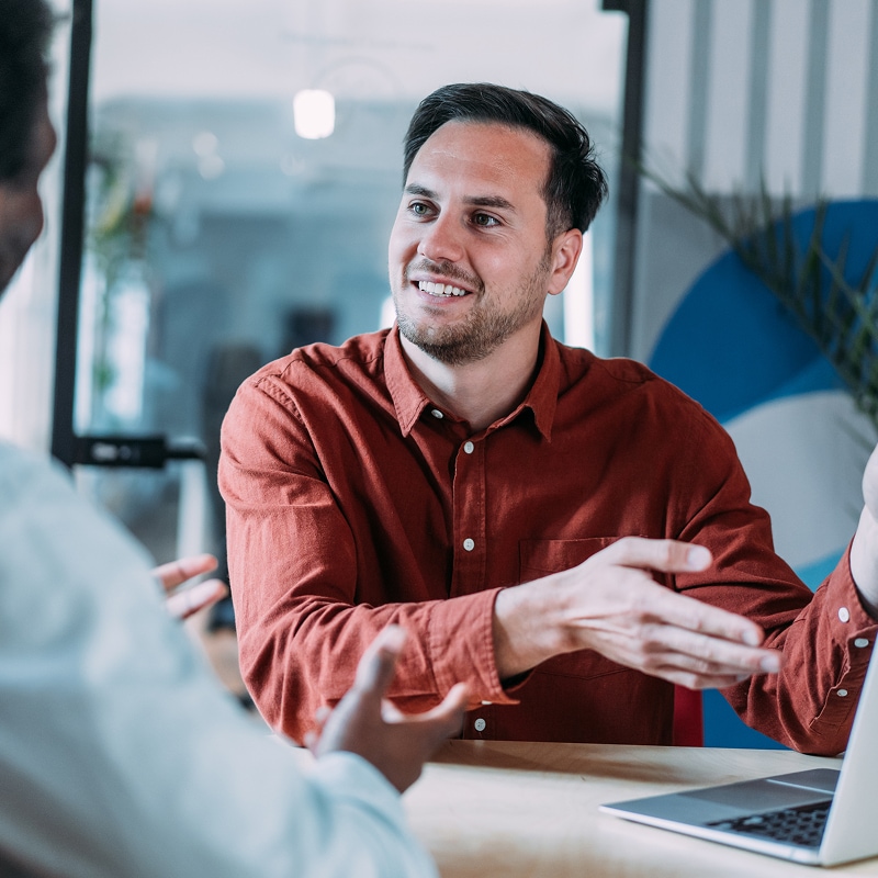 Professional discussing project details across desk in meeting.
