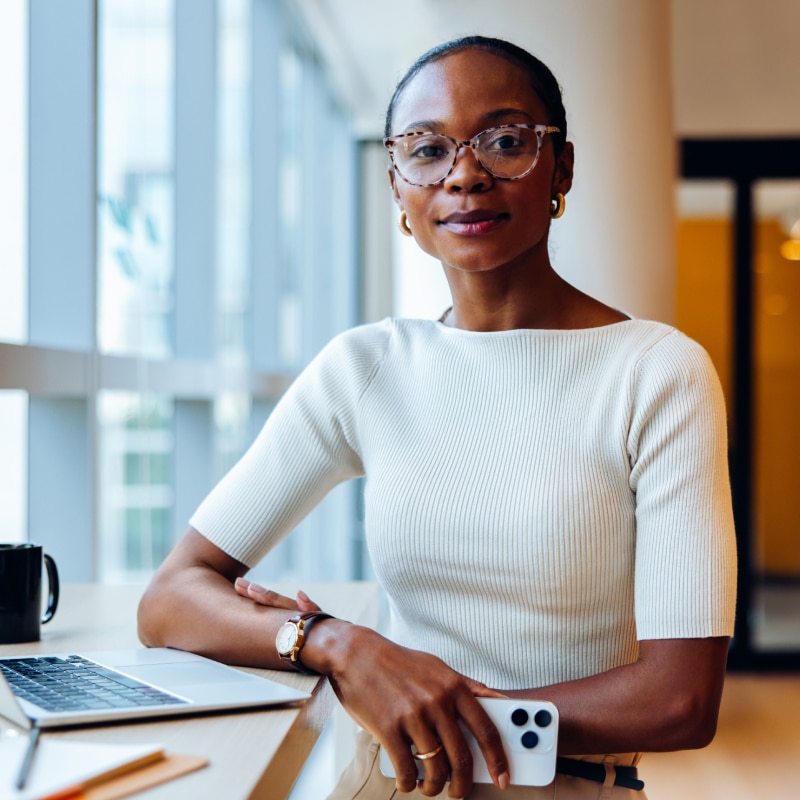 Technology professional works at a desk with a laptop in a bright office.
