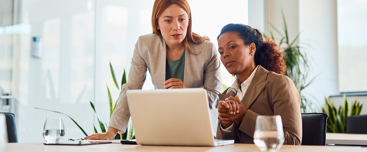 Two professionals review strategy on a laptop in a modern office.