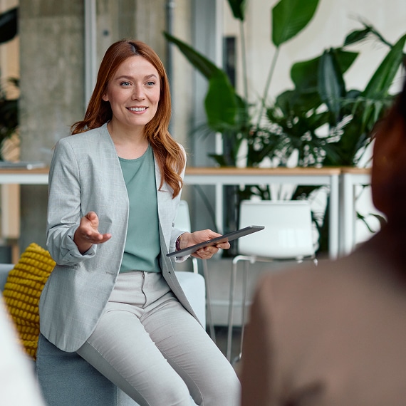 Professional presenting with tablet during a collaborative office meeting.