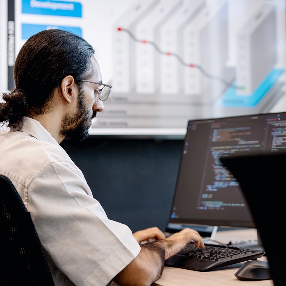 Professional typing code on laptop with performance chart displayed behind.