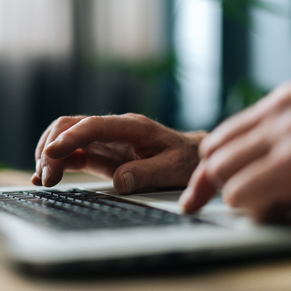 Close-up of hands typing on laptop keyboard during focused work session.