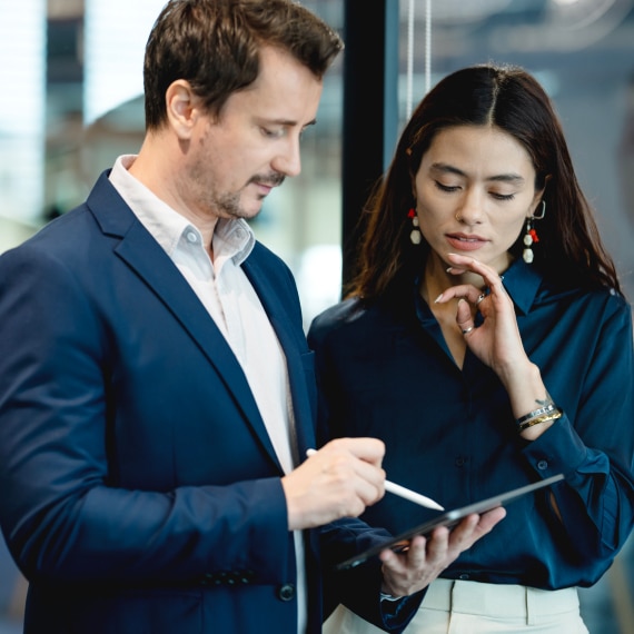 Two colleagues review governance metrics on a tablet, discussing data activation strategy in a modern office.