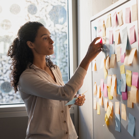 Professional organizes colorful sticky notes on a planning board during a brainstorming session.