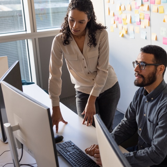 Colleagues collaborate at a computer workstation.