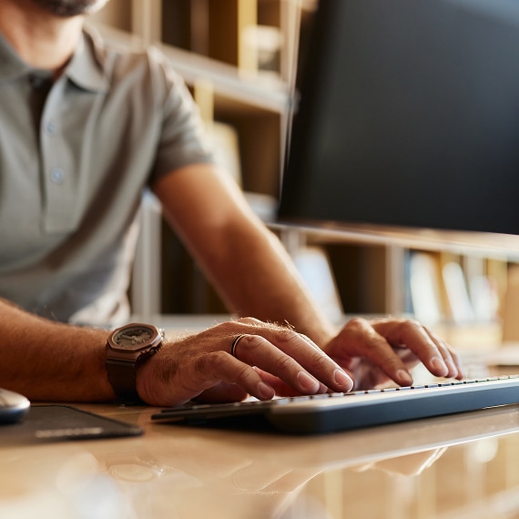 Professional typing on keyboard at modern workstation with monitor.