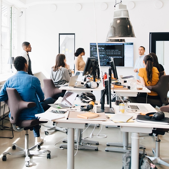 Team of professionals collaborating around desks during technical meeting.