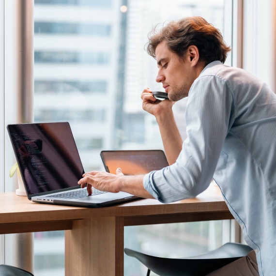 Security analyst reviewing code on a laptop to assess vulnerabilities and strengthen risk posture.