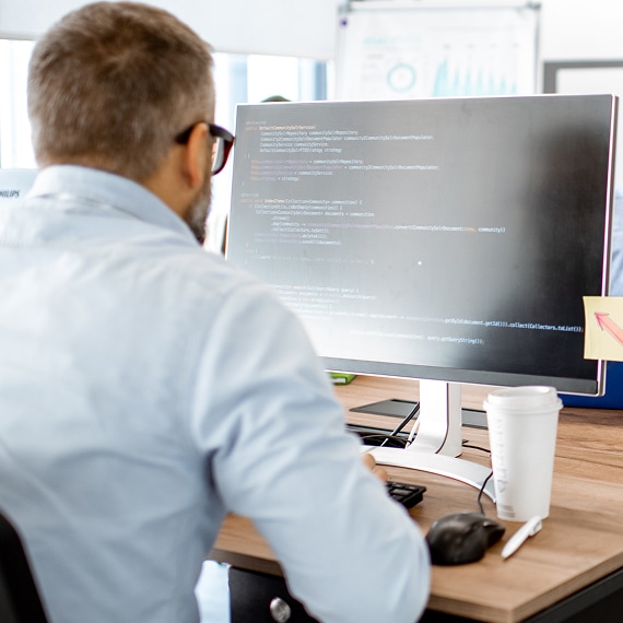 Professional reviewing information on a large desktop monitor in an office.