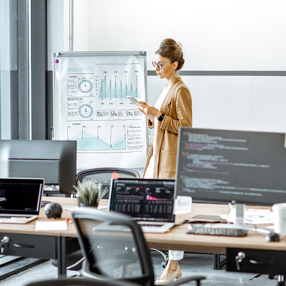Analyst presenting data charts and graphs on a whiteboard in a meeting room.
