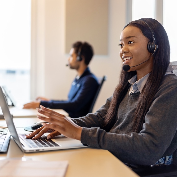 Customer service representative smiling while assisting a client through a headset.