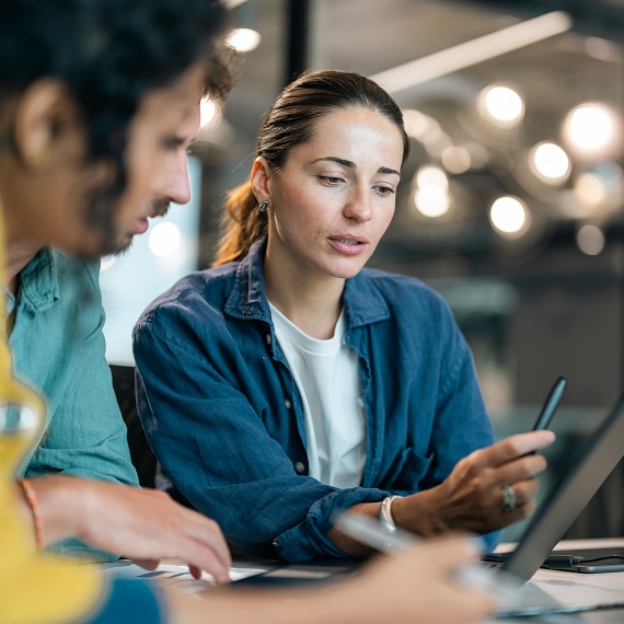 Two colleagues collaborating over a tablet during a focused office discussion.