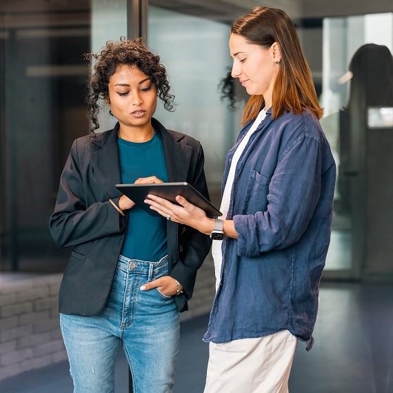 Two professionals reviewing content on a tablet in a contemporary office setting.