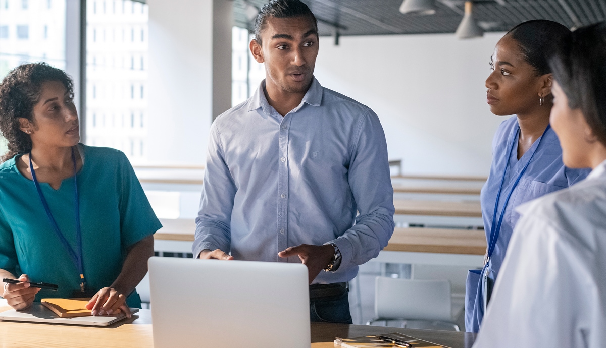 Team of professionals gathered around a laptop discussing project details in a modern office.
