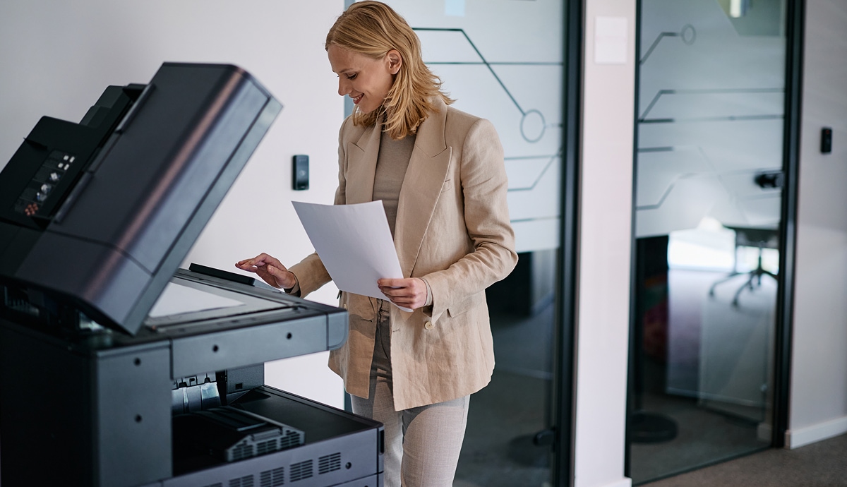 Business professional printing documents on a multifunction printer in a modern workspace.