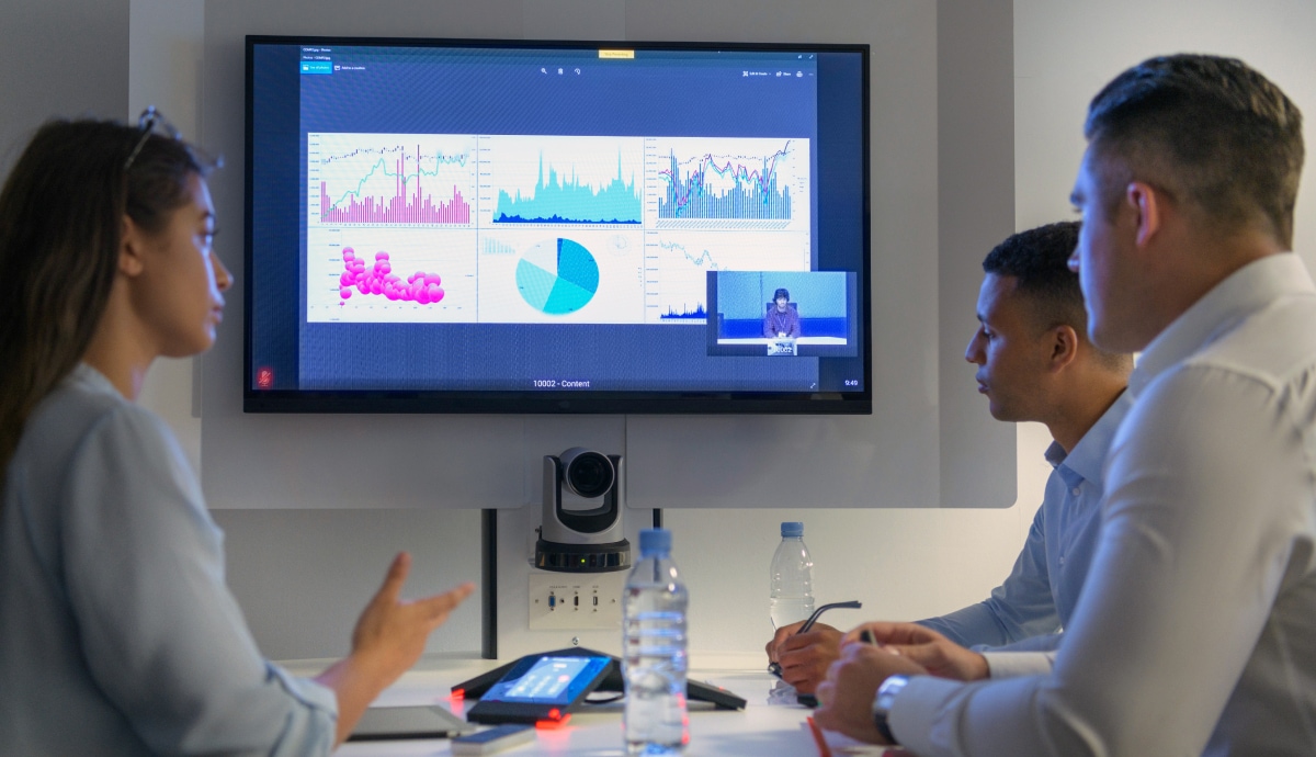Team members reviewing performance charts on a conference room screen during a data meeting.