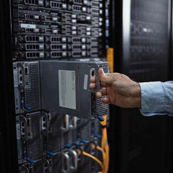 IT specialist installs a server drive into a rack inside a data center cabinet.
