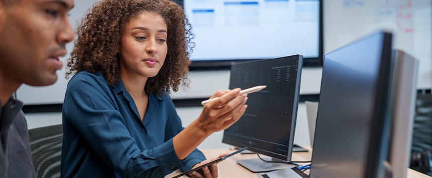 Software developers discussing programming code and planning how to create innovative software at co-working office. Two software developers checking programming code on computer screen. working through a coding problem together.