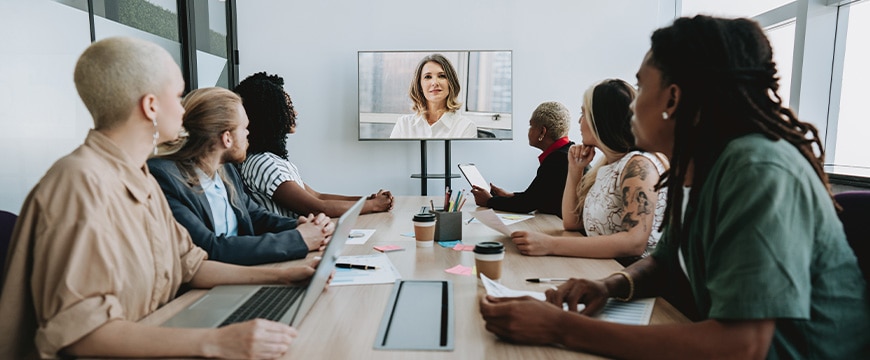 Hybrid team meeting with video conferencing camera at center of conference table